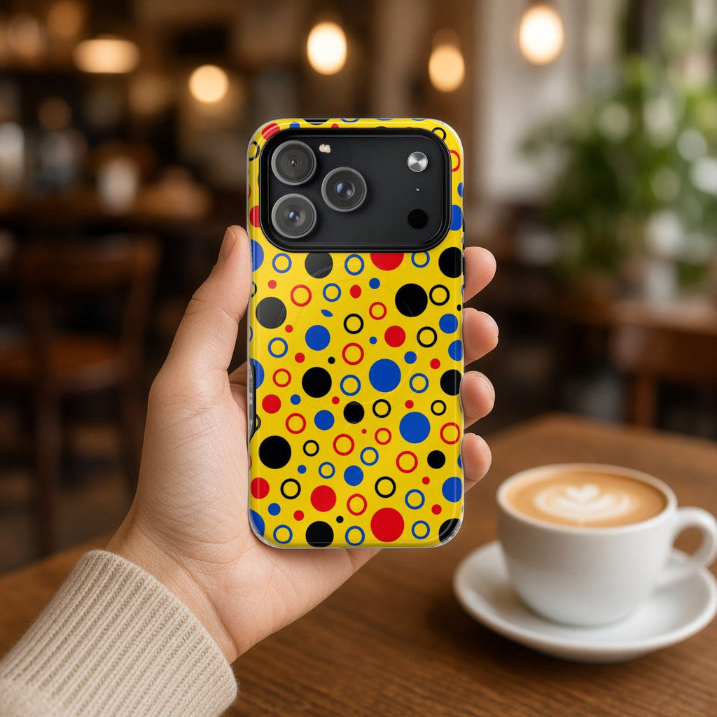 Hand holding the Bubble Outlines magnetic iPhone case in a cafe beside a latte