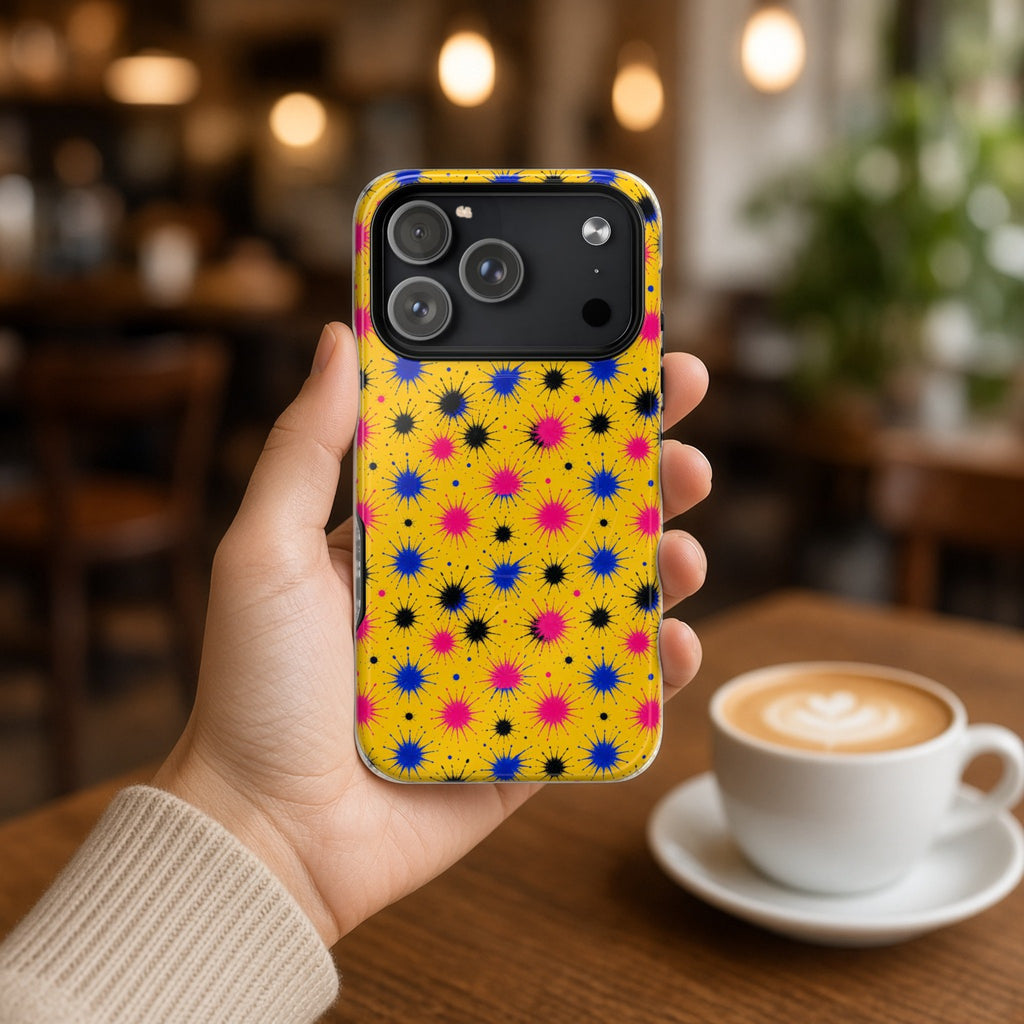 Hand holding the Splash Crowns magnetic iPhone case in a cafe beside a latte