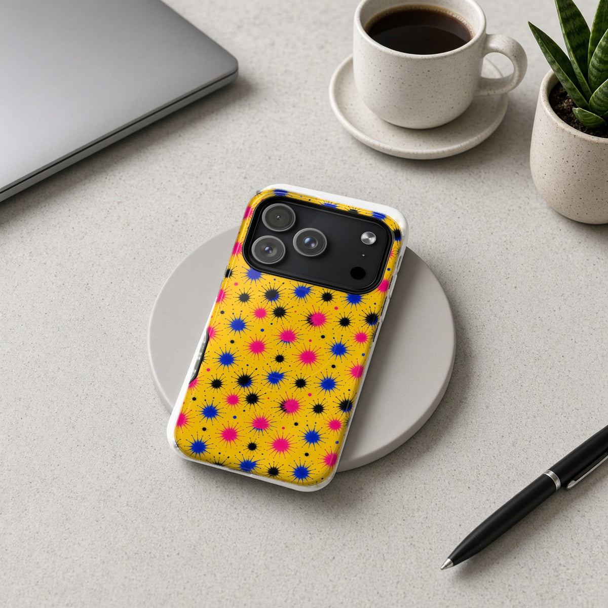 Splash Crowns magnetic iPhone case on a wireless charging pad on a grey desk